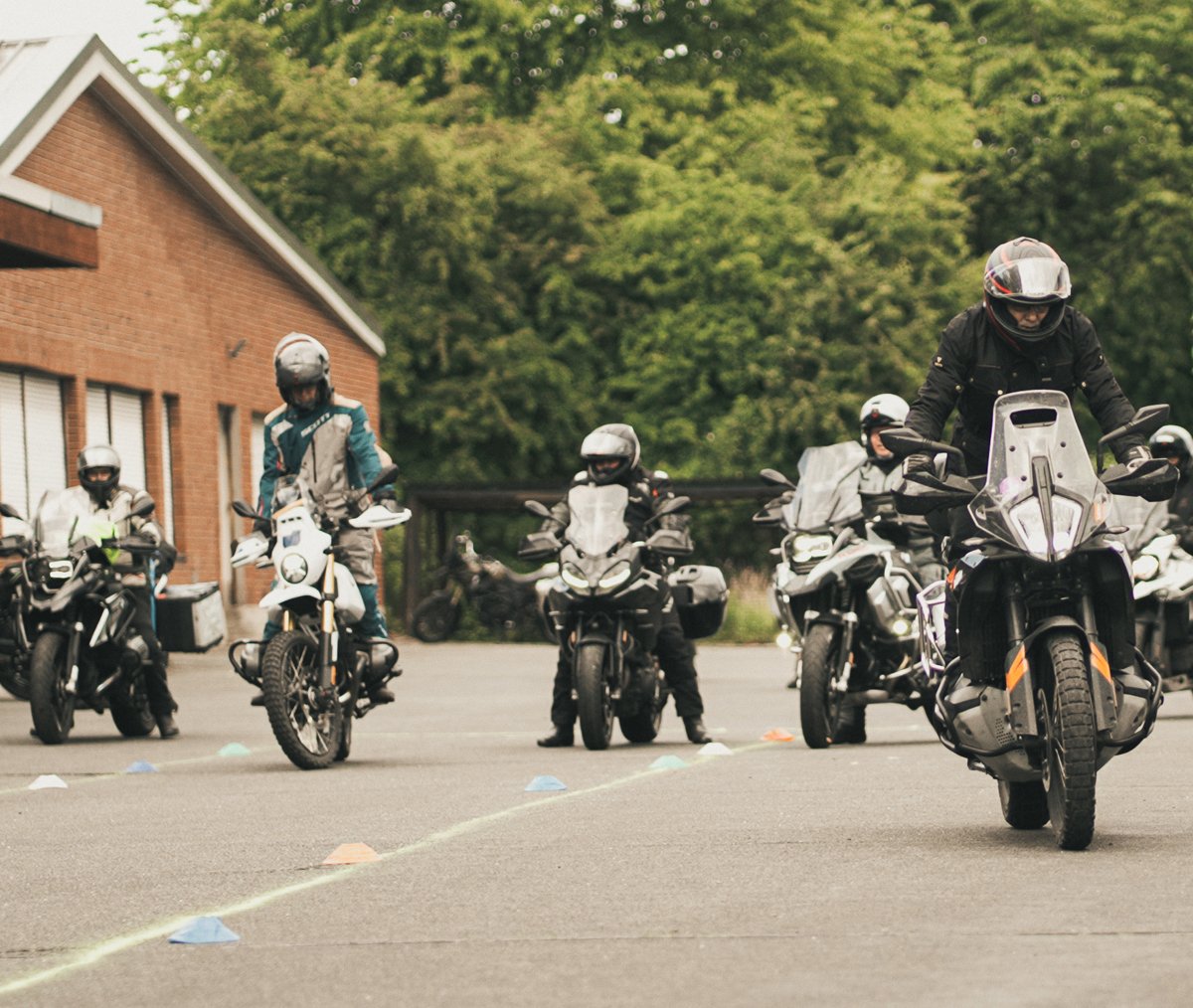 Motorradfahrer üben langsames Fahren auf einem abgesperrten Parcours.