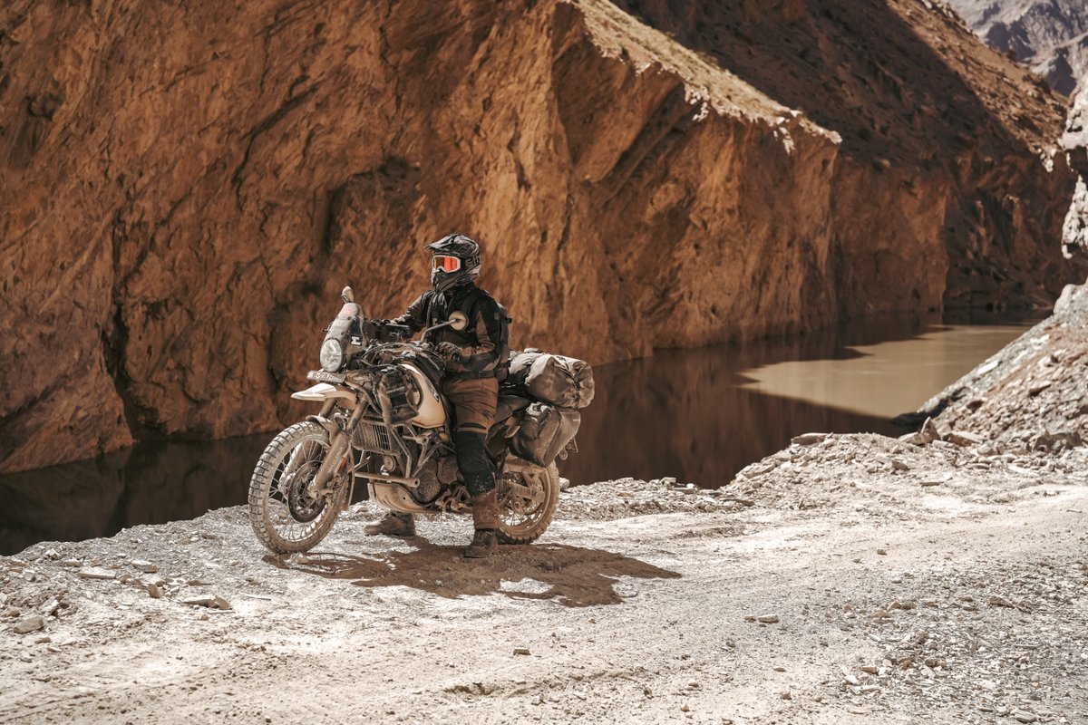 Motorradfahrer mit Adventure-Bike in einer felsigen Schlucht an einem Fluss
