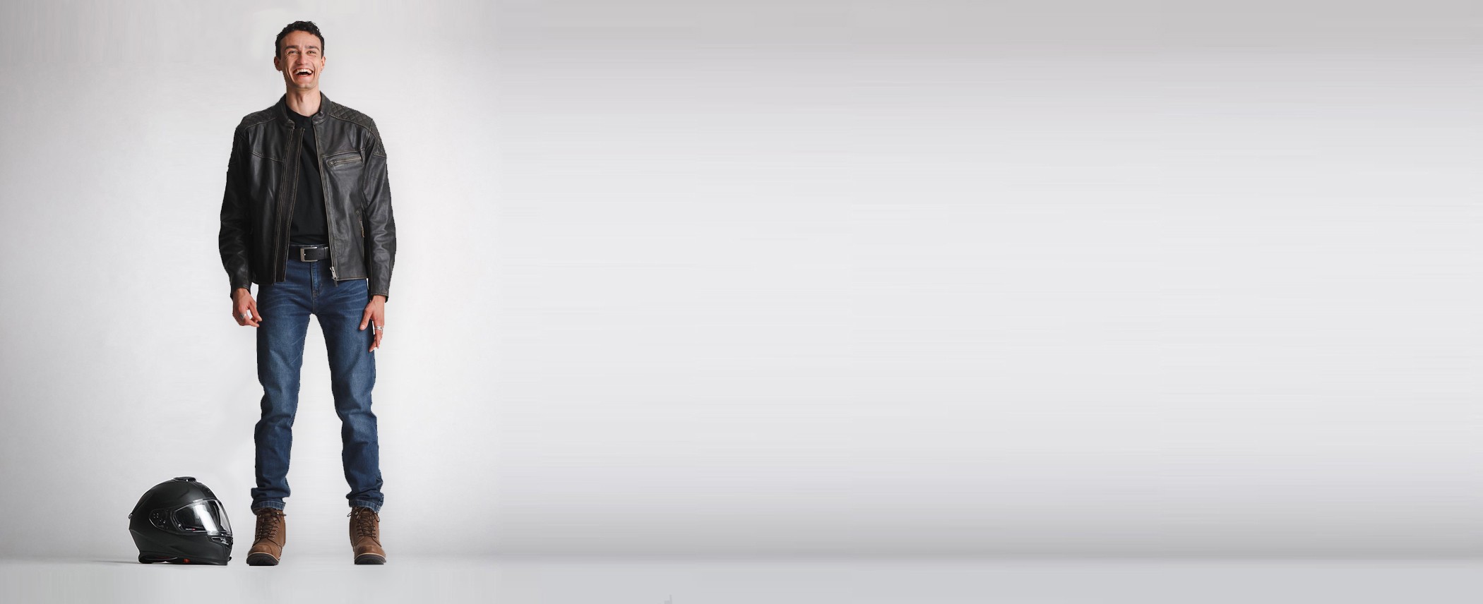 A motorcyclist standing next to a helmet