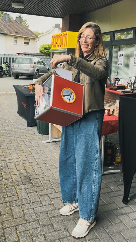 Mitarbeiterin zieht einen Zettel aus einer Gewinnspielbox auf dem Modeka-Event.