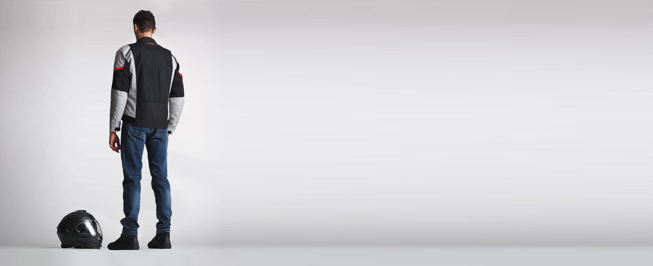 A motorcyclist standing next to a helmet