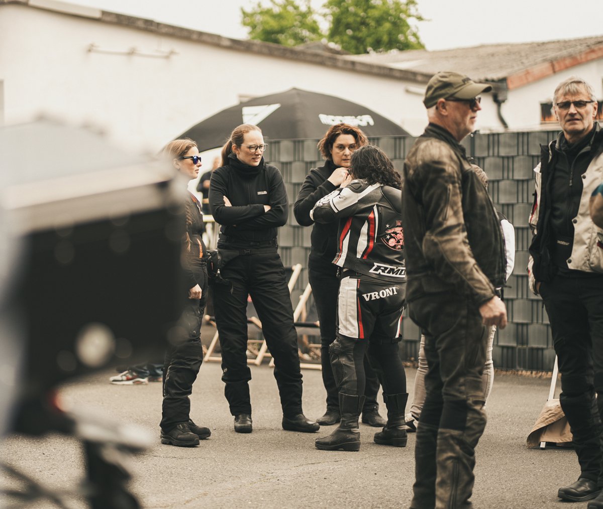Gruppe von Motorradfahrern steht im Freien zusammen und unterhält sich auf einem Parkplatz.