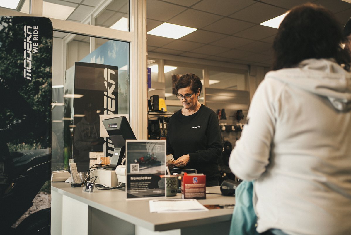 Mitarbeiterin bedient eine Besucherin an der Kasse im Modeka-Store.