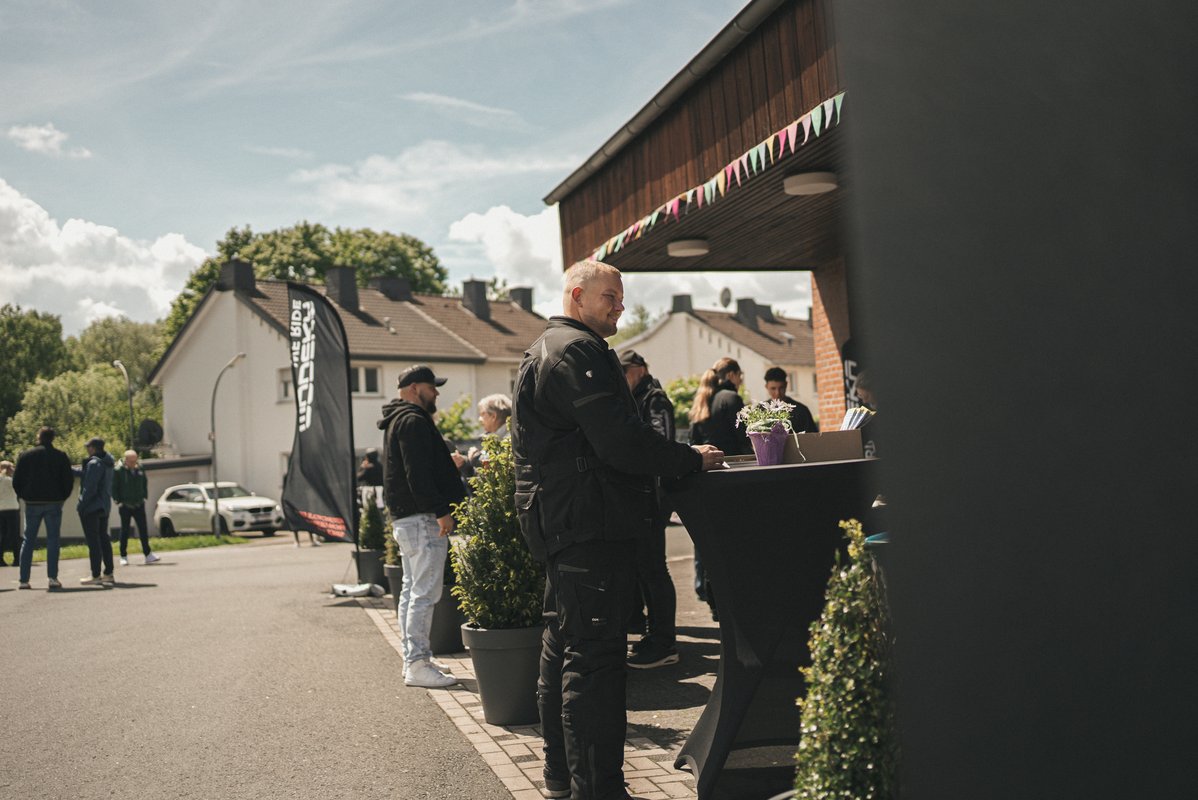 Besucher stehen an Stehtischen vor dem Modeka-Gebäude und unterhalten sich auf dem Eventgelände.