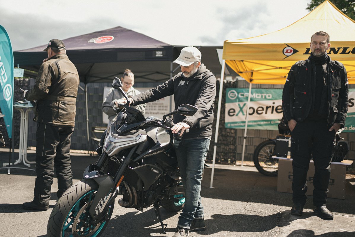 Besucher betrachten ein ausgestelltes Motorrad zwischen Ausstellerzelten auf dem Modeka-Event.
